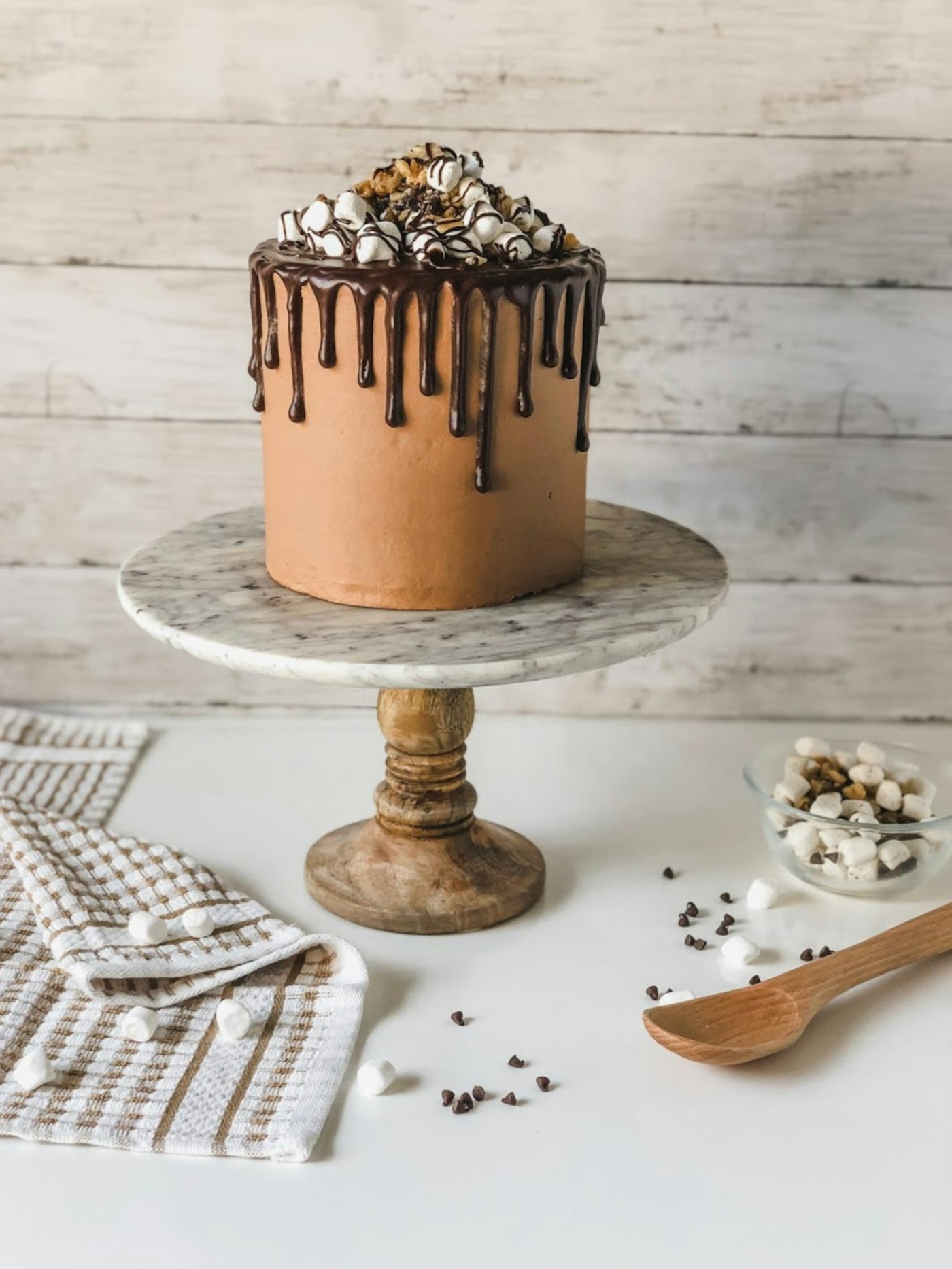 Bizcocho de chocolate con goteo y toppings sobre una base de mármol